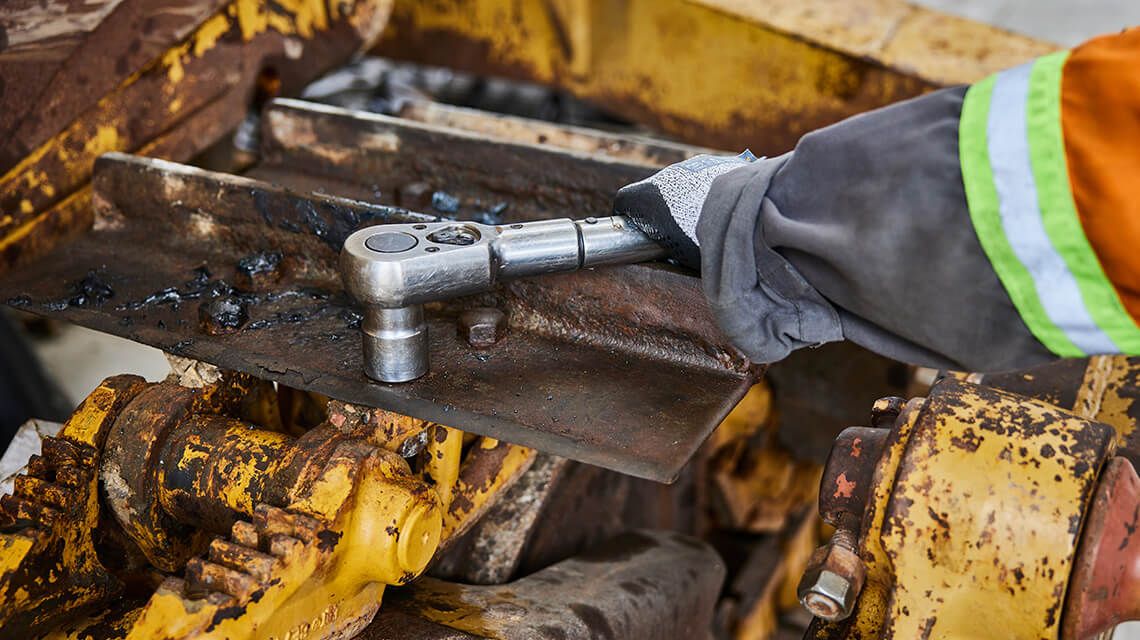 Worker using a socket wrench on machine