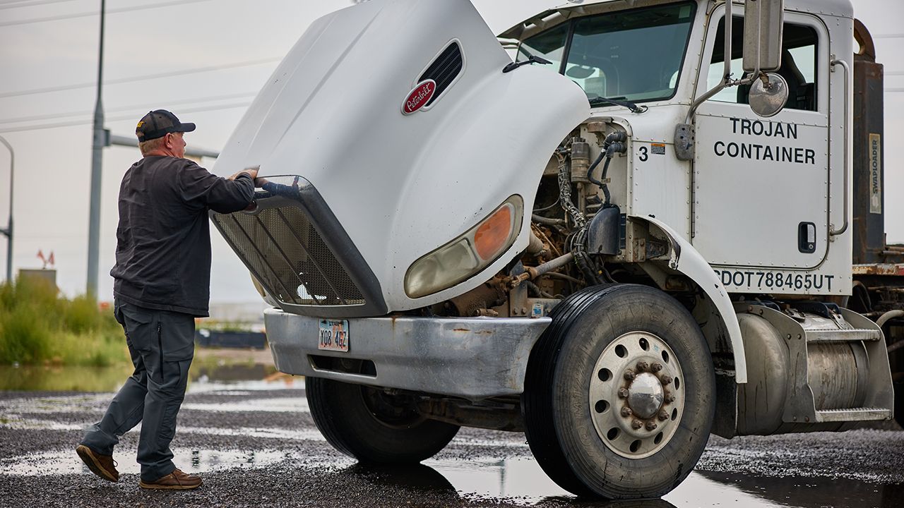 a truck driver adjusting the hood of his truck