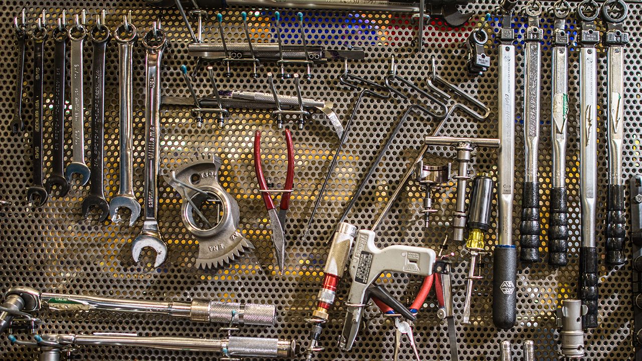 a variety of tools on a wall-mounted peg board