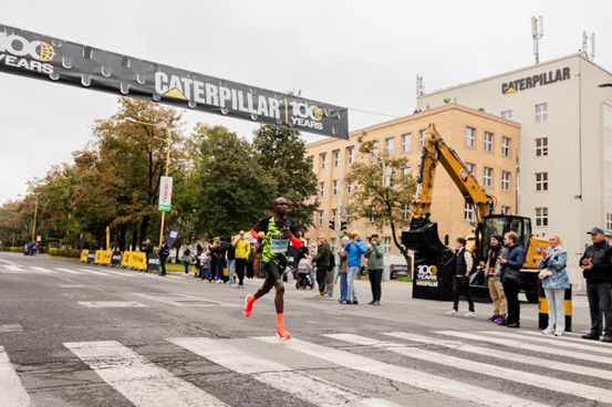 Runners with equipment and Caterpillar sign in background