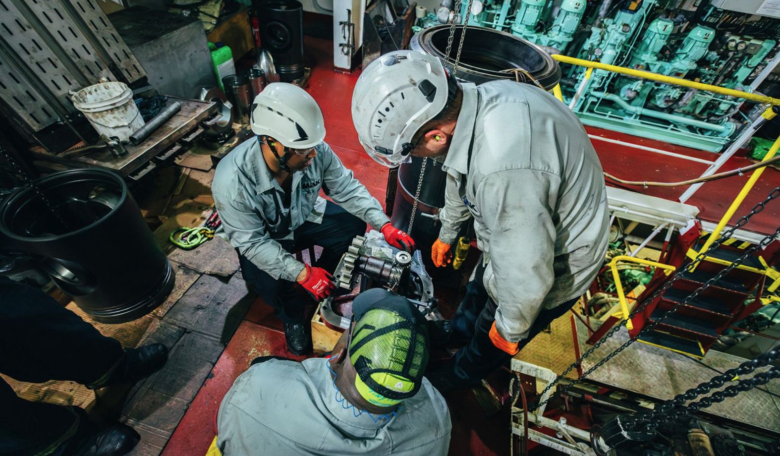 three MaK employees working on a MaK part