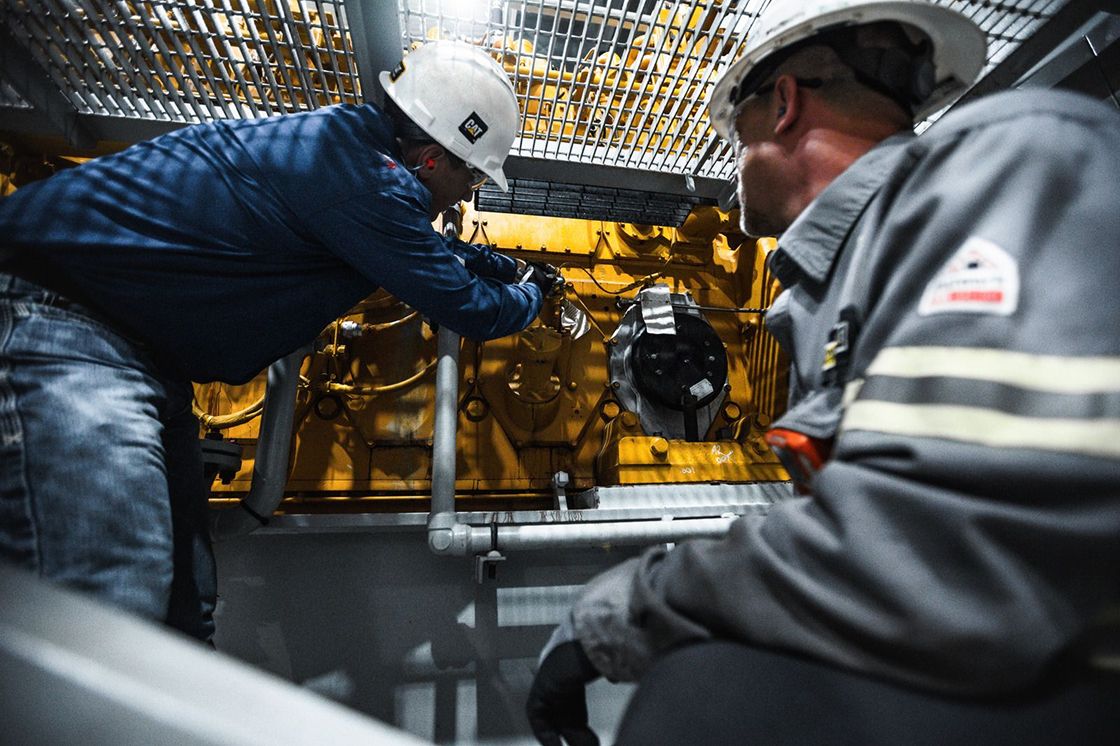 Two Caterpillar employees working on an engine