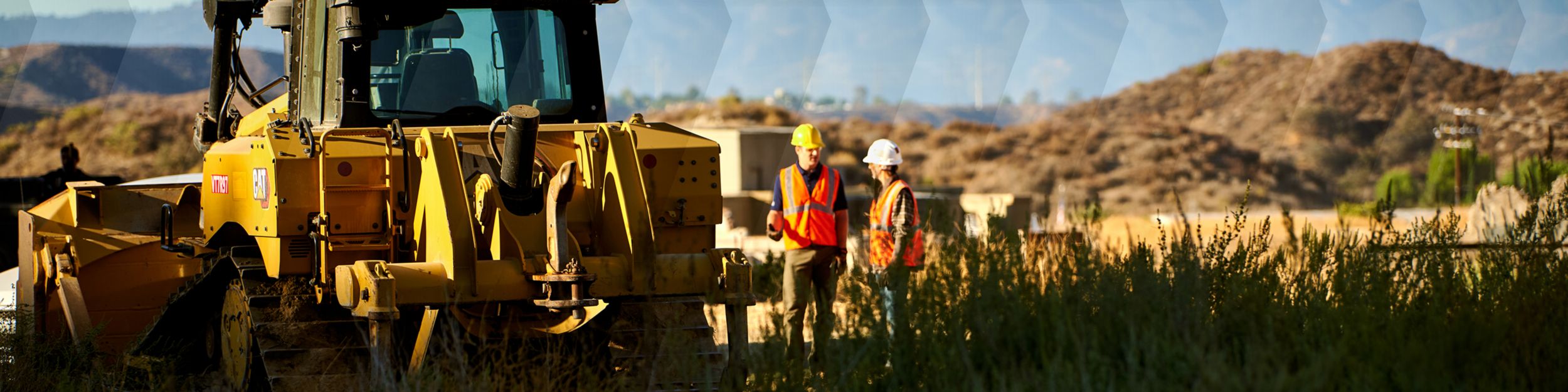 2 operators standing in a field; machine in the foreground