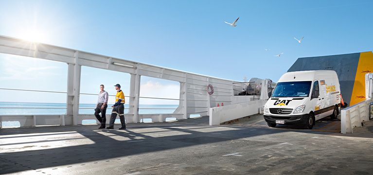Cat dealer walking with a customer on a ferry deck, with a service truck nearby.