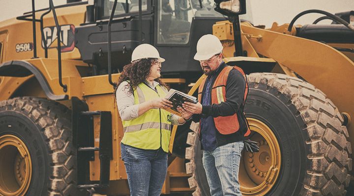 Two Cat workers consulting over notes