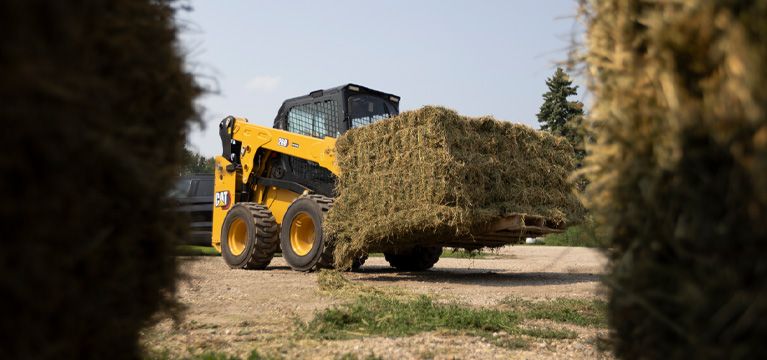 Minicargadora con una paca de heno