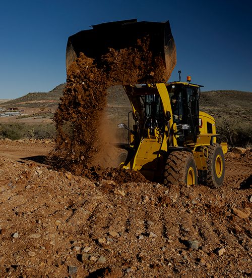 Carregadeira de rodas despejando terra da caçamba.