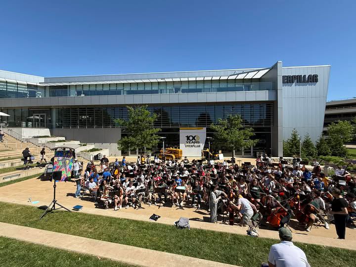 A crowd of people gathered outside of the Caterpillar Visitors Center.