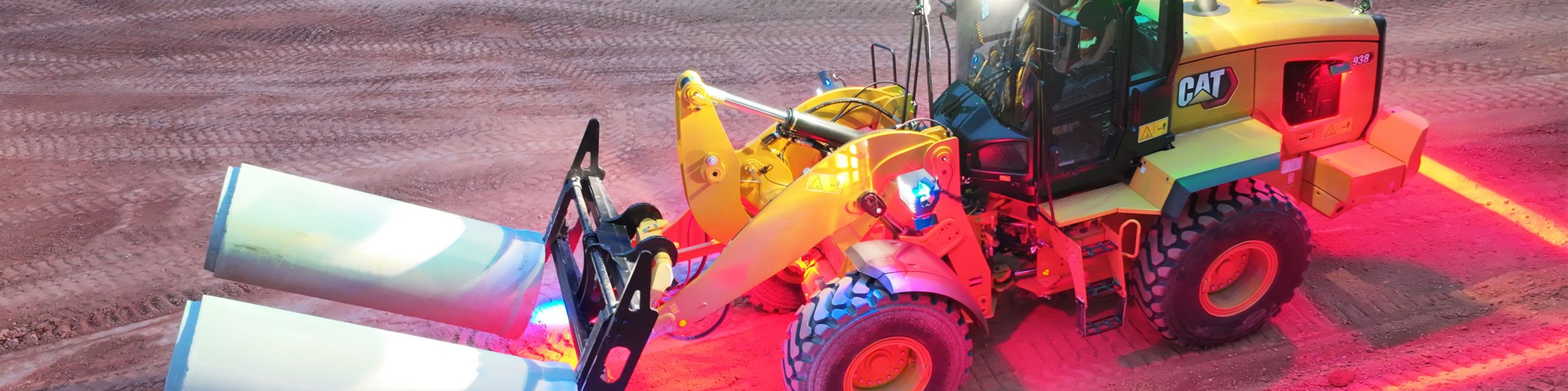 Cat equipment hauling concrete tubes on construction site