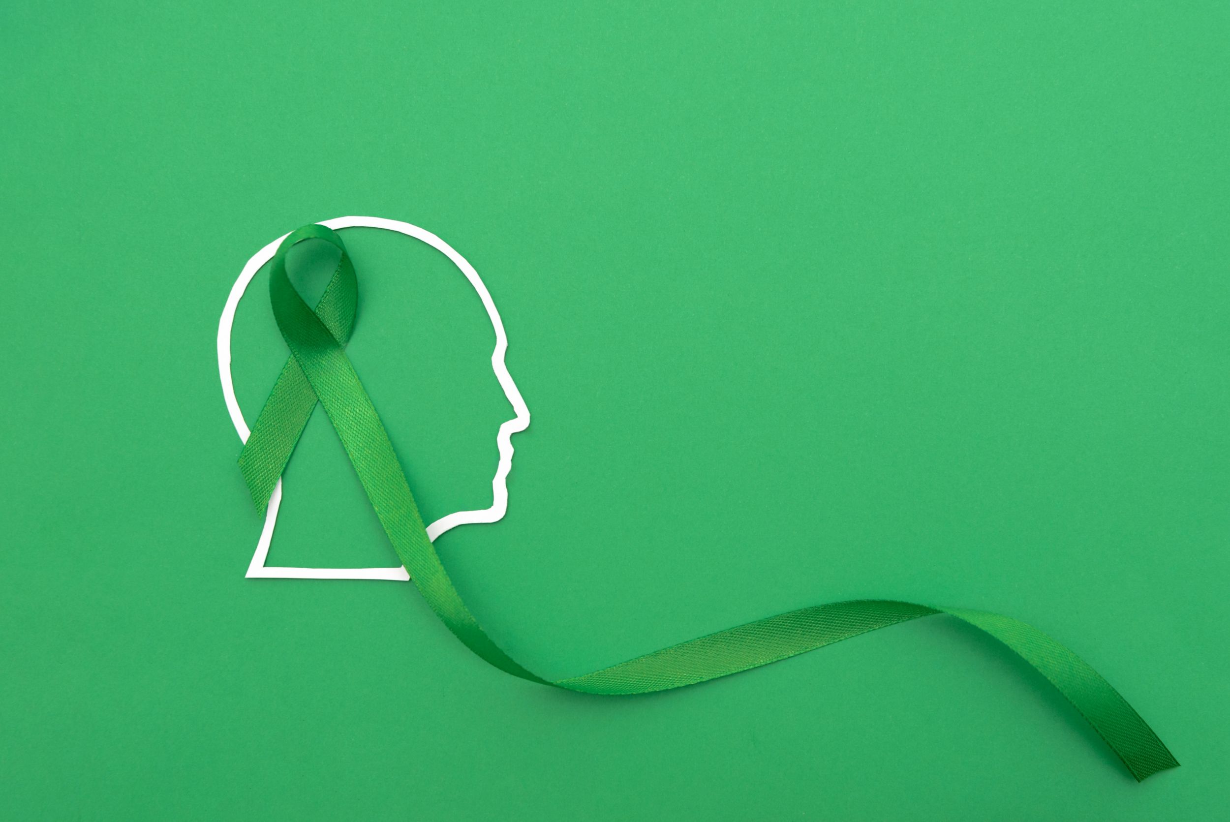 Profile outline of human head with a green ribbon on a green background