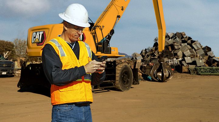 construction professional reviewing the contents of a tablet with machines in the background