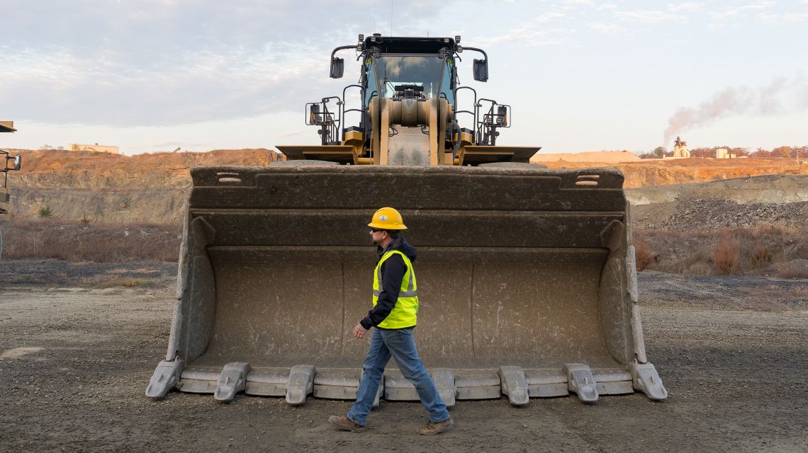 Man walking in front of a Cat machine