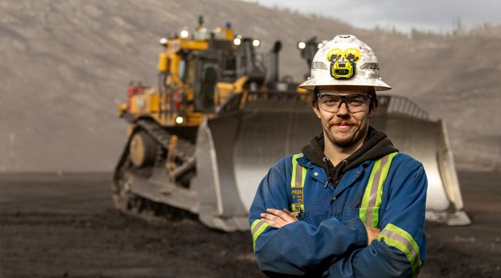 Man Posing in Front of a Cat Dozer