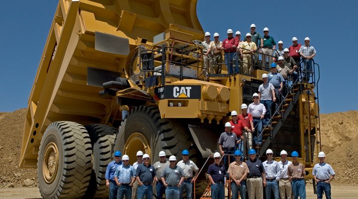 Group Photo in Front of a Cat Mining Machine