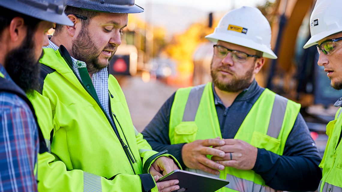 four construction professionals discussing what's on the screen of a tablet