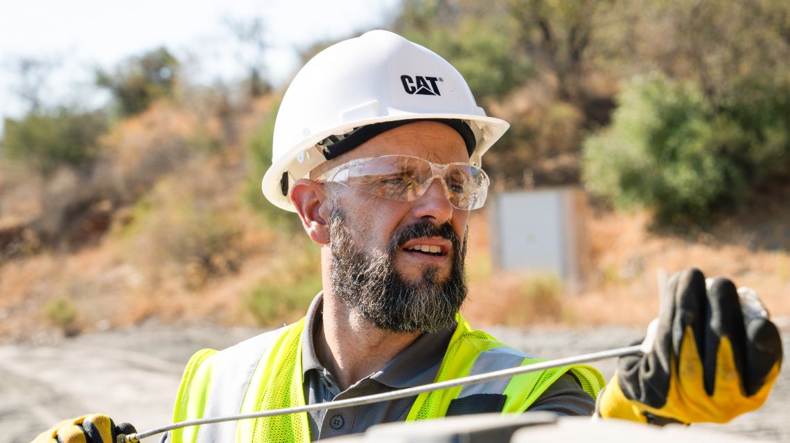 construction professional checking the fluids of a piece of road construction equipment