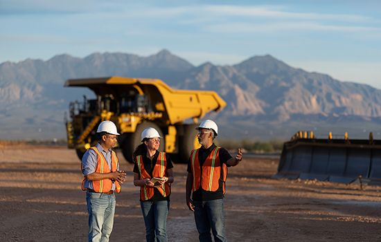 people talking in front of a mining truck