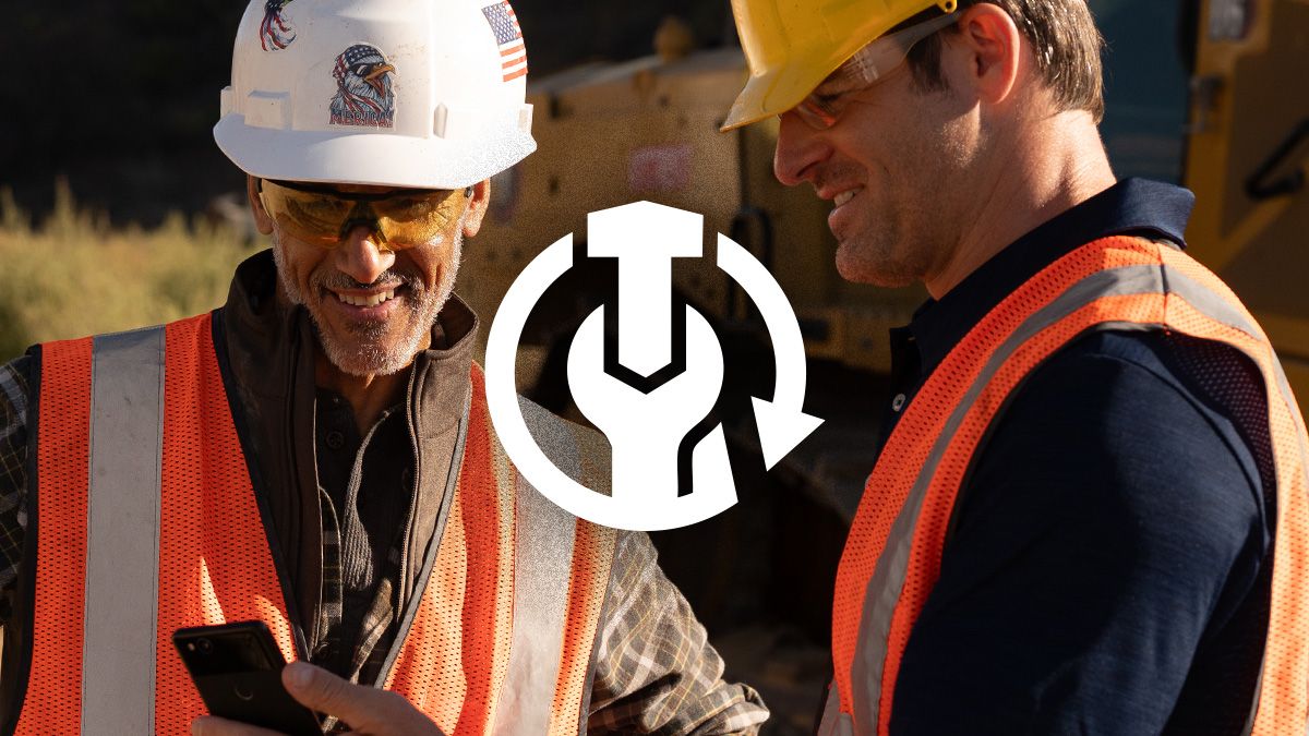 Construction professionals wearing appropriate safety gear smiling while reviewing rebuild data on a smartphone at a job site.