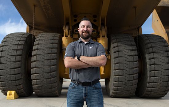 employee standing in front of a mining truck