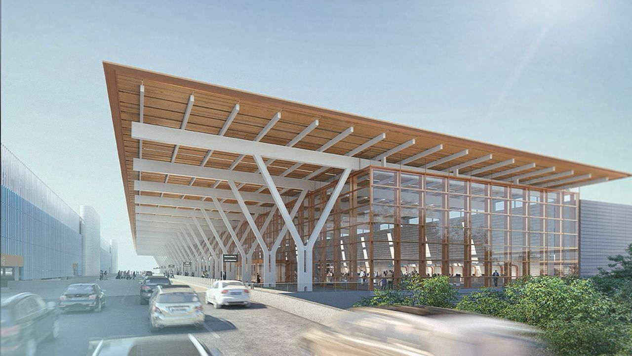 Airport terminal building with an extended roof structure and surrounding paved areas.