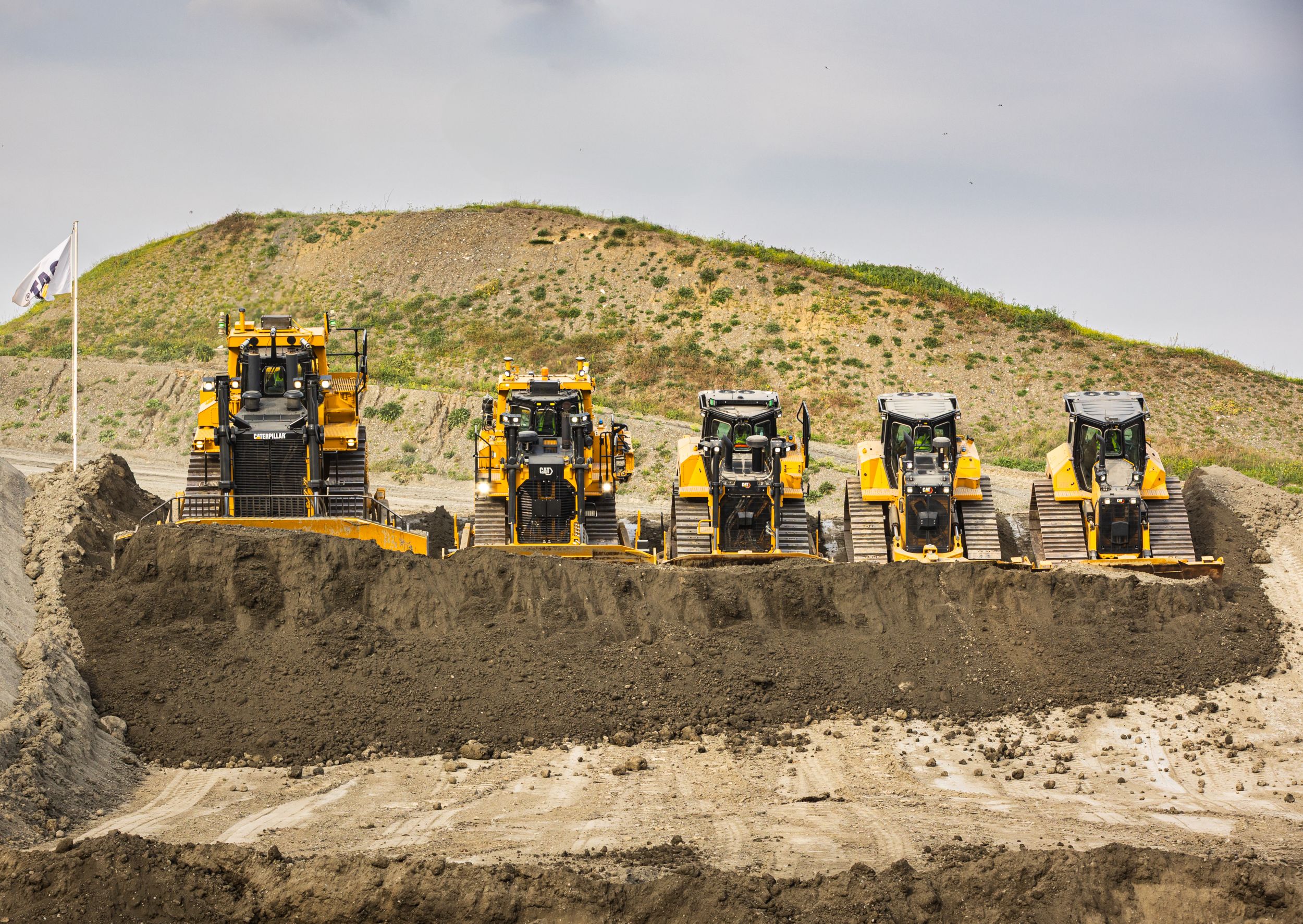 Cat machines lined up pushing dirt