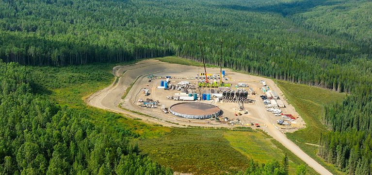 Aerial view of an oil and gas rig site in an evergreen forest