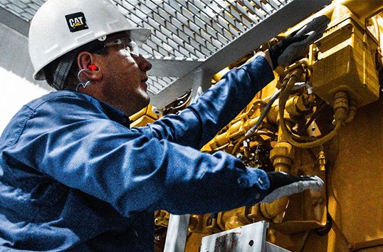 image of a man working on a cat engine