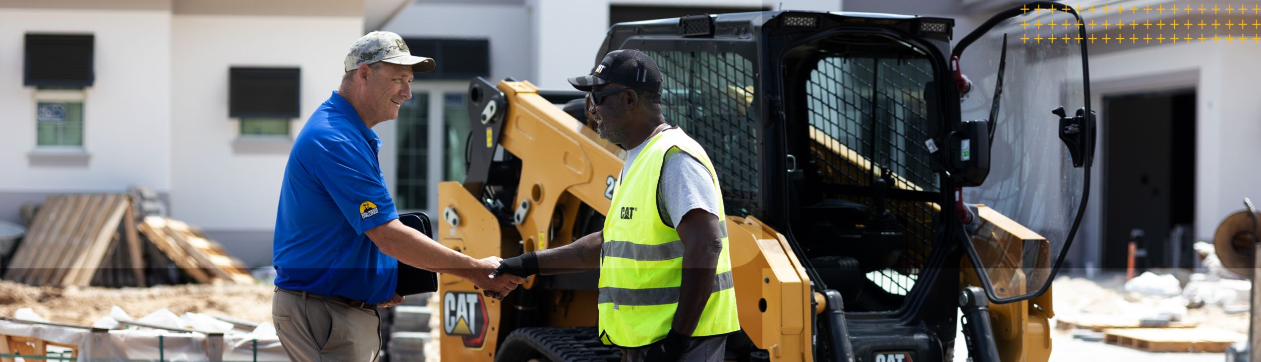 two workers shaking hands in front of Cat equipment