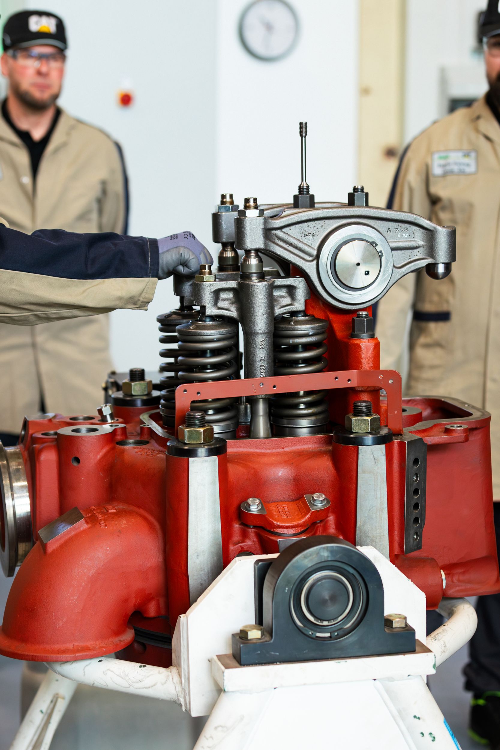 Technician inspecting valve train components on a large MaK engine cylinder head during maintenance or service training.