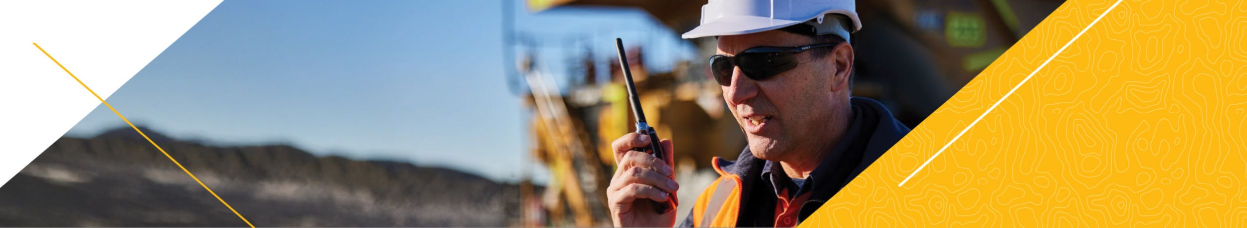 Cat employee talking into walkie on work site