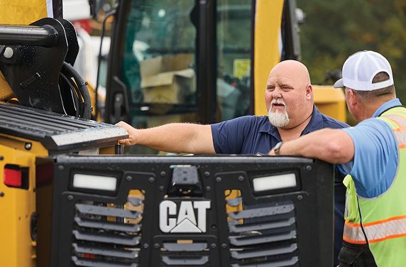 Cat dealer talking to a customer in a dealer lot