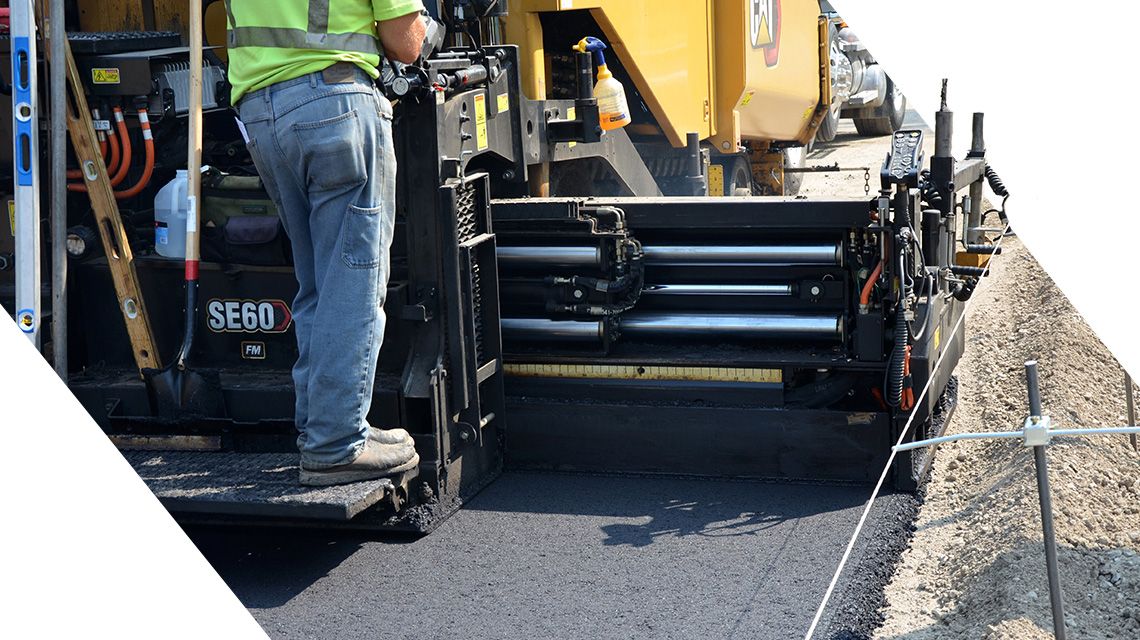 Operator going over fresh asphalt with a paver