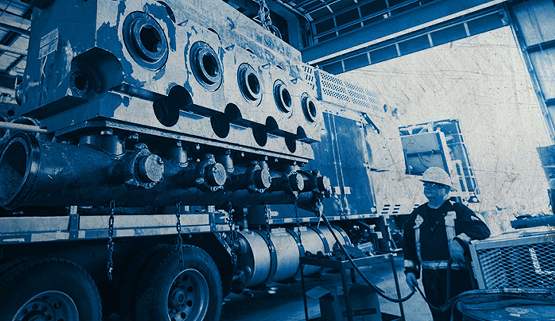An employee stands next to a large truck in a warehouse