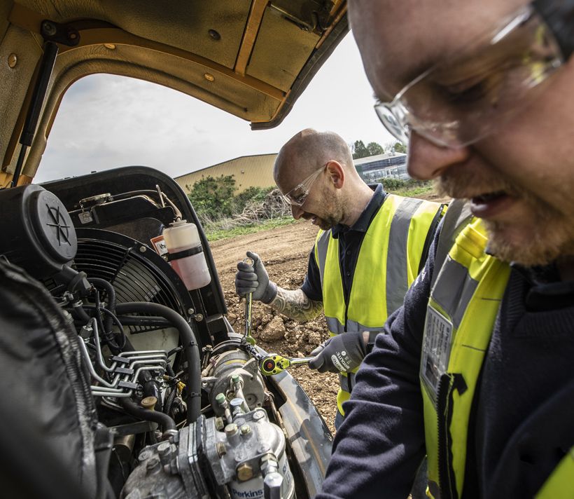 two men fixing an engine