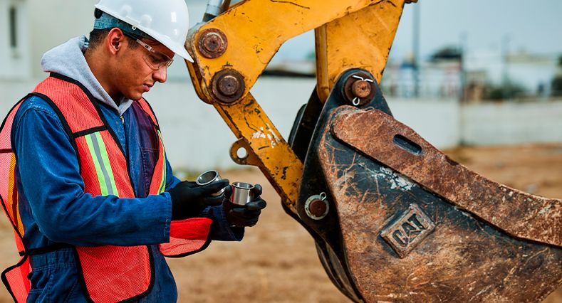 Operador de pie junto al cucharón de la excavadora
