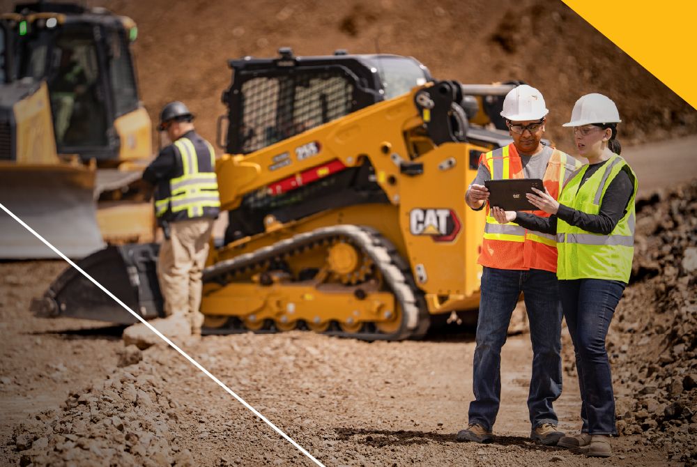Cat dealer and customer consulting on a worksite while Cat machines are being serviced