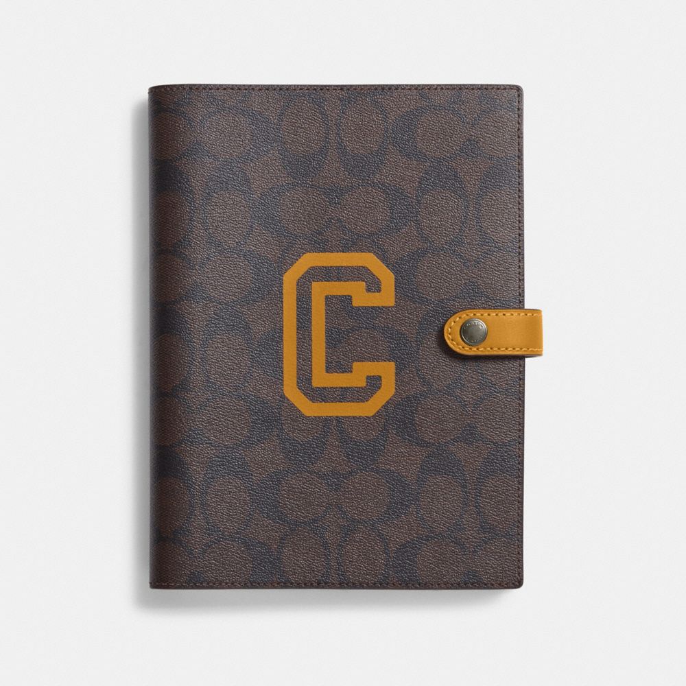 COACH CC055 Notebook In Signature Canvas With Varsity Motif BLACK ANTIQUE NICKEL/BROWN/BUTTERCUP