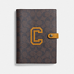 COACH CC055 Notebook In Signature Canvas With Varsity Motif BLACK ANTIQUE NICKEL/BROWN/BUTTERCUP