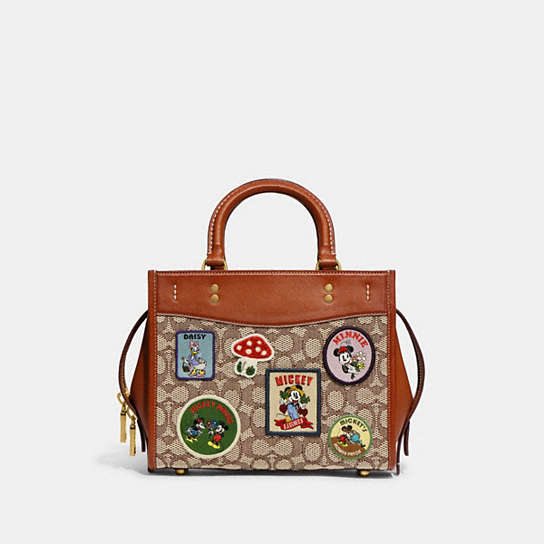 CH416 - Disney X Coach Rogue 25 In Signature Textile Jacquard With Patches Brass/Cocoa Burnished Amber Multi