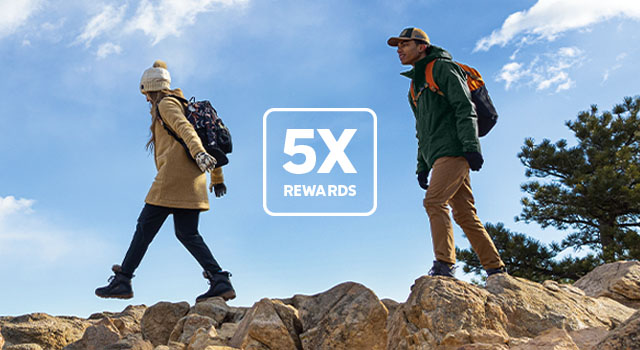 5X Rewards. Man and woman in warm Columbia gear hiking a on rocks.