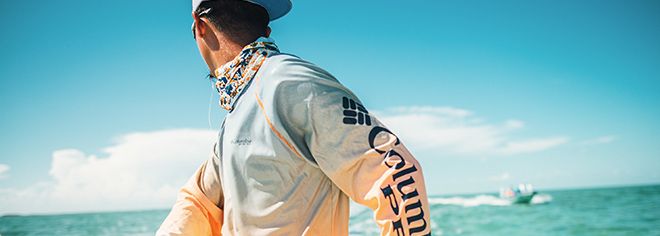 A man on a boat wearing a Columbia PFG long-sleeve shirt with Omni-Shade Sun Deflector technology. 
