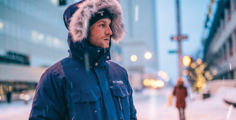 A man wearing a parka with faux- fur-trimmed hood.