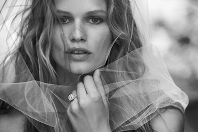 A black-and-white photo of model Anna Ewers wearing a white veil and a DY Capri engagement ring in platinum with diamonds.