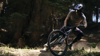 Mountain bike rounding a turn on a trail and wearing the Fox Dropframe Pro helmet
