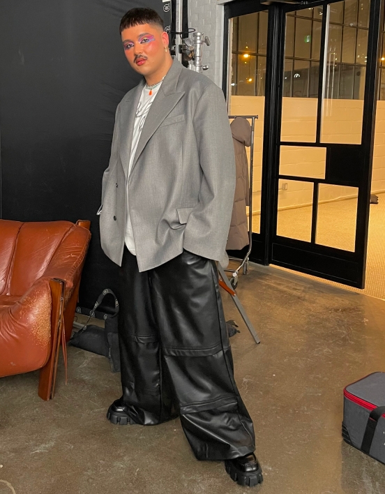 Michael posing to show off his full look of an oversized grey blazer, white shirt, and black loose pants.