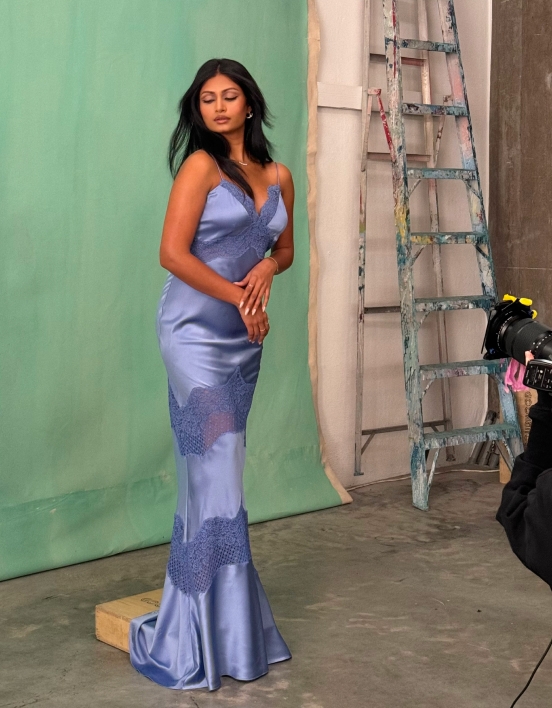 Krishna posing in front of a green backdrop, wearing a blue slip dress and jewellery.