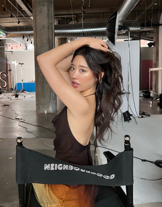 Jessica posing with her hands over her head while sitting in a director’s chair.