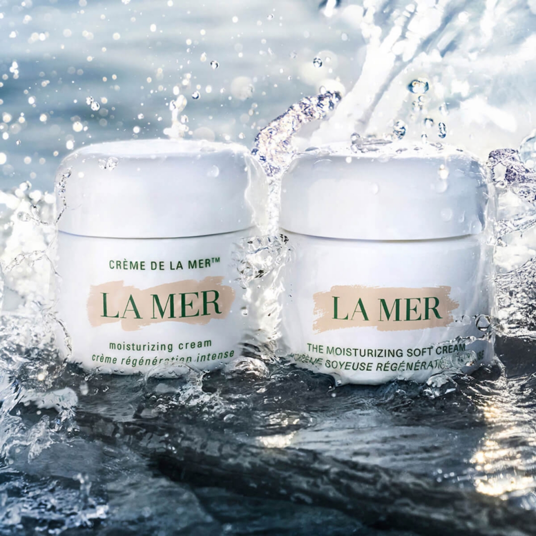 Two white La Mer skincreams being splashed with water