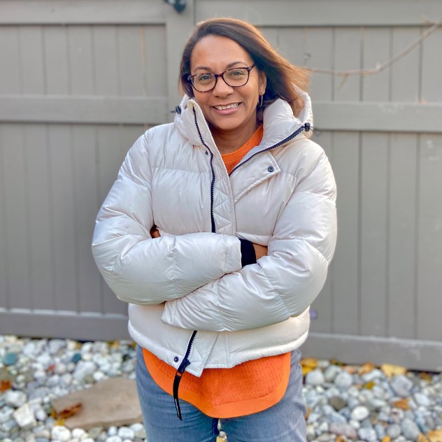 Alicia hanging out in backyard in the winter, wearing a puffer coat.
