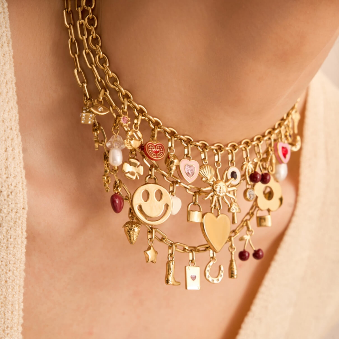A model wearing gold necklaces with colourful charms